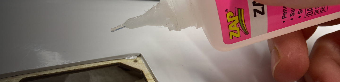 A modeler applies CA to an aileron or flap servo door cover.
